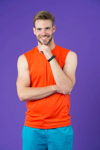 Homem feliz com smartwatch esporte em fundo violeta. Esportista sorrir em colete laranja e shorts. Acessório de moda para treinamento. Nova tecnologia para um estilo de vida saudável. Desporto ou fitness e bem-estar — Fotografia de Stock