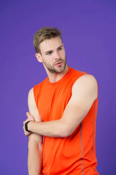 Homme au visage réfléchi posant en vêtements de sport, fond violet. Le type à poils porte une chemise sportive et un appareil de fitness. Concept d'accessoires sportifs. Homme avec accessoire sportif numérique moderne — Photo