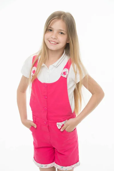 Щасливе дитинство та догляд за дітьми. Маленька дівчинка посміхається в рожевому комбінезоні ізольовано на білому. Дитина посміхається довгим світлим волоссям. Дитяча модель в модному загальному. Стиль моди і тенденція — стокове фото