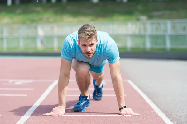Man runner on start position at stadium. Runner in start pose on running surface. Man run outdoor at running track. Sport and athletics concept. Sportsman on concentrated face ready to go — Stock Photo, Image