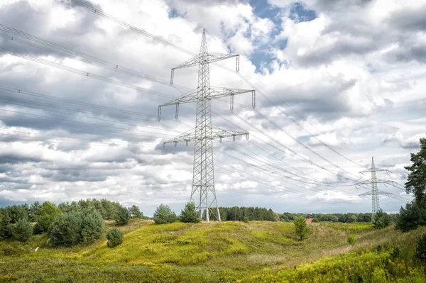 在自然景观上的电力塔。传输塔在多云的天空。电塔结构用电源线。高压后室外。能源与生态学 — 图库照片