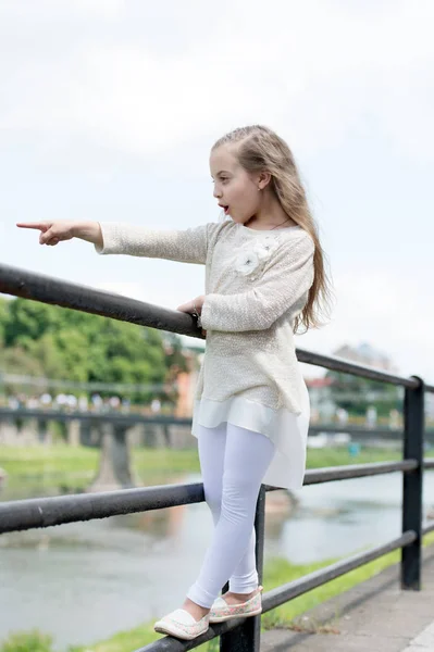 Kid dívka s dlouhými vlasy chodí u řeky, řeky na pozadí. Dívka dítě turistické si památky a procházky. Koncept dovolenou. Školačka na dovolené nebo holka si cestování a vyhlídkové — Stock fotografie