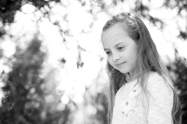 Chica con el pelo largo en la cara tranquila, fondo de la naturaleza desenfocado. Chica con peinado tierno trenza. Niña con peinado de trenza. Niño chica pelo largo se ve lindo y tierno, de cerca. Concepto de peinado — Foto de Stock