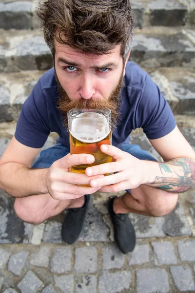 Facet po odpoczynku z piwa z beczki. Człowiek z broda i wąsy piwo posiada, podczas gdy siedzi na zadnich, schody kamienne podłoże. Hipster na ścisłe twarz picie piwa odkryty. Koncepcja piwo — Zdjęcie stockowe
