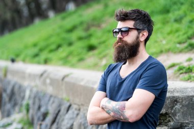 Berber ve stil kavramı. Sakal ve bıyık katı yüz, Doğa arka plan, defocused olan adam. Sakallı hippi açık havada duran ise kendinden emin görünüyor. Sakallı adam modern güneş gözlüğü takıyor