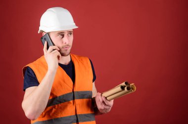 Dostum, kask içinde mimar inşaat telefon, kırmızı zemin üzerine denetlemektedir. Müzakere kavramı. Mühendis, mimar, Oluşturucu meşgul yüzündeki konuşuyor Smartphone cep telefonu ile ayrı tutma planları, kopya alanı ise