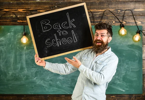 Gözlük öğretmen okul için başlıklı yazı tahtası tutar. Adam sakal ve bıyık mutlu yüz memnuniyetle öğrencilerin, kara tahta arka plan ile. Lise kavramı — Stok fotoğraf