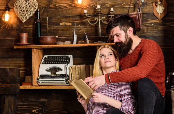 Pareja enamorada leyendo poesía en un ambiente cálido. Concepto romántico de noche. Señora y hombre con barba en caras de ensueño con libro, leyendo poesía romántica. Pareja en madera vintage interior disfrutar de la poesía — Foto de Stock