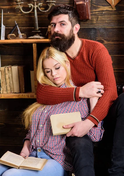 Romantic evening concept. Couple in wooden vintage interior enjoy poetry. Couple in love reading poetry in warm atmosphere. Lady and man with beard on dreamy faces hugs and reading romantic poetry — Stock Photo, Image