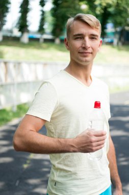 Susuz adamın su şişesi Stadı ile. Sporcu plastik şişe güneşli açık ile. Susuzluk ve dehidrasyon. İçme suyu sağlık için. Spor aktivitesi ve enerji