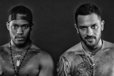 Atletler çıplak kas sandıkları ve pazı ile kendine güvenen yüzleri. Seksi kas torsolar ile çocuklar sporcular. Dövme sanat kavramı. Çekici, koyu arka plan maço kas dövmeli torsolar ile bak