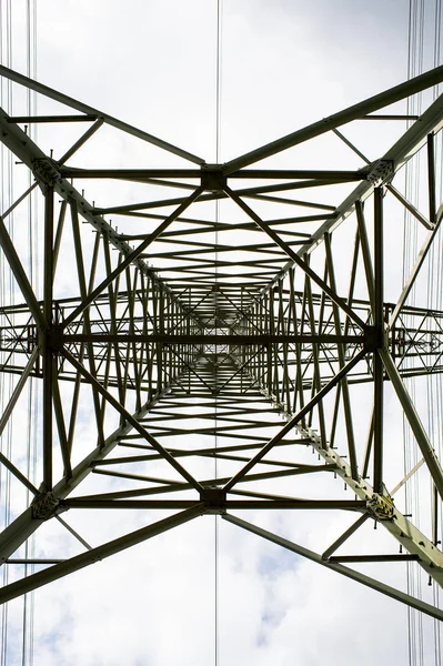 Vista inferior de la torre de transmisión. Torre de energía en el cielo nublado. Estructura de pilón de electricidad para línea eléctrica. Puesto de alto voltaje al aire libre. Energía y ecología — Foto de Stock