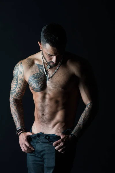 Deseo con sexualidad y atracción. El stripper muestra un torso sexy. Deportista con seis paquetes y abdominales. Atleta con músculos bíceps y tríceps. Moda hombre con tatuaje quitarse jeans — Foto de Stock