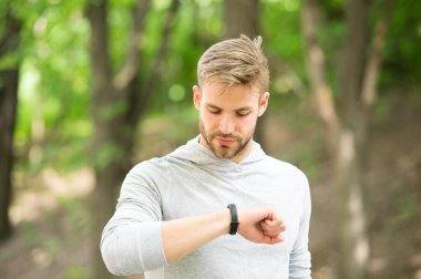 Adımölçer cihazıyla atletizm eğitimi. Meşgul yüz kontrolü yapan sporcu, spor takip cihazı, doğa geçmişi. Fitness takip cihazı ya da adım sayacı olan bir atlet. Spor aleti kavramı