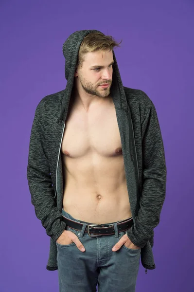 Macho met sexy romp in casual sweatshirt. Man met baard draagt capuchon op violette achtergrond. Modemodel in hoodie. Actieve levensstijl en gezondheidsactiviteit. Modestijl en trendconcept — Stockfoto