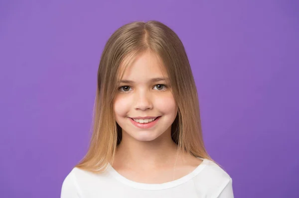 Beauty look en huidverzorging. Meisje glimlach op violette achtergrond. Kind met frisse huid op schattig gezicht. Schoonheid kind met gelukkige look en lang blond haar op paarse achtergrond. Jeugd en Kinderopvang — Stockfoto