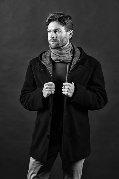 Autumn or fall fashion outfit. Man wear casual coat with scarf. Fashion model pose on dark background. Confidence and harisma. Style or trend and vogue, black and white