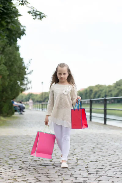 女孩在平静的面孔购物运载袋子, 都市背景。长头发的小女孩喜欢购物。时尚女孩购物与粉红色的袋子。购物理念女孩喜欢买衣服 — 图库照片