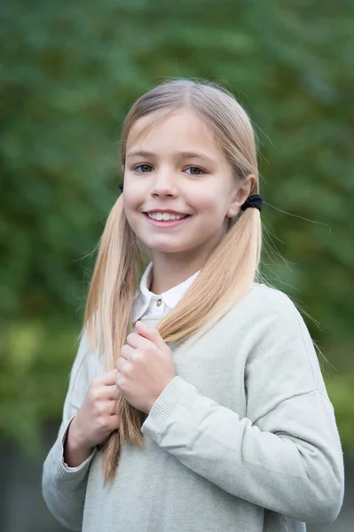 Acconciatura e concetto di cura dei capelli. Ragazza sul viso sorridente in posa con due code, sfondo verde naturale. Ragazza ama guardare carino, elegante e alla moda. Ragazza con i capelli lunghi sembra adorabile — Foto Stock