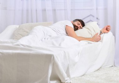 Sakin yüz beyaz çarşafımda yatıyor adam, yastık. Uykuda kavramı. Maço sakal uyku ile rahatlatıcı, nap, sahip rest. Adam arka plan üzerinde battaniye, beyaz perdeler ile kaplı yatak, döşeme