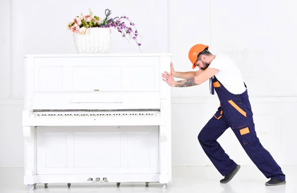 Hombre de vista lateral tratando de reubicar el piano pesado aislado sobre fondo blanco. Hombre fuerte construyendo músculos en el trabajo — Foto de Stock