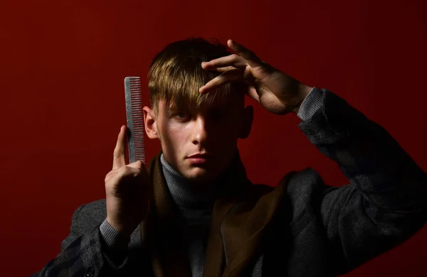 Peluquero en traje y bufanda con peine sobre fondo rojo — Foto de Stock