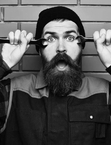 Bearded brutal caucasian mechanic holding metallic wrenches — Stock Photo, Image