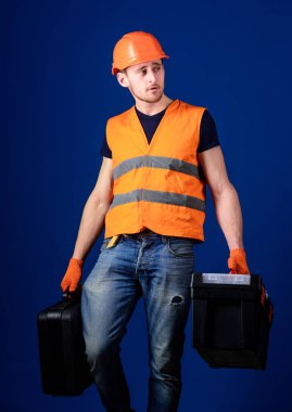 Donanımlı tamirci kavramı. İşçi, tamirci, tamirci, Oluşturucu profesyonel araçlar ile sakin yüz taşıdığı çanta üzerinde. Araç kutusu ve araç, mavi arka plan ile bavul kask, kask içinde adam tutar