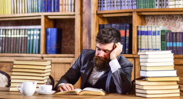 Hipster sits in vintage interior and enjoys reading.