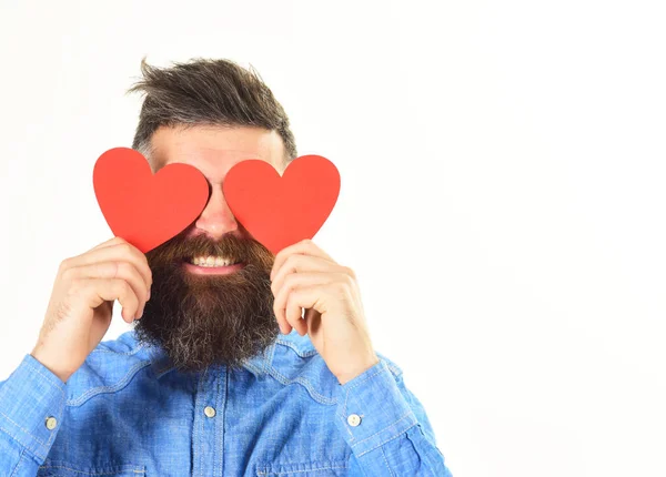 El hombre con barba sostiene corazones de papel rojo como anteojos . —  Fotos de Stock