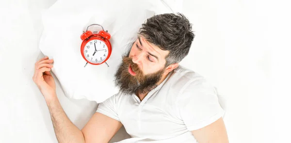 Hombre con la cara conmocionada se encuentra en la almohada cerca del despertador . —  Fotos de Stock