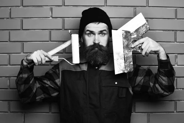 Peintre barbu homme tenant divers outils de construction avec visage surpris — Photo