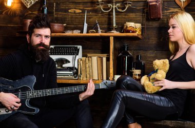 Romantik tarih kavramı. Adam oyun gitar Bayan ise oyuncak ayı elinde tutar. Rahat yüzleri aşık çift romantik atmosferinin keyfini çıkarın. Çift Romantik akşam, ahşap iç arka plan geçirmek