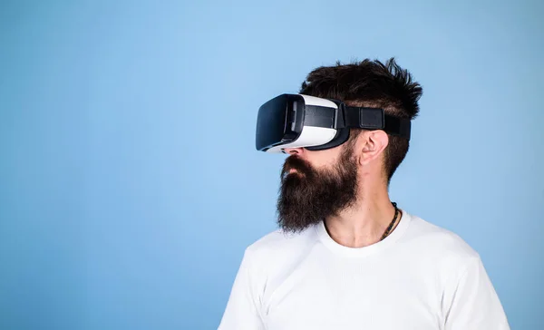 Homem com barba em óculos VR, fundo azul claro. Conceito de tecnologia digital. Cara com cabeça montada exibir interagir em realidade virtual. Hipster no rosto sério desfrutar de realidade virtual com gadget — Fotografia de Stock