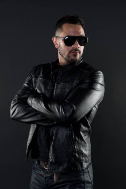 Silah ile kendine güvenen adam stand katlanmış. Sakallı adam trendy güneş gözlüğü. Deri ceket ve kot moda model. Moda ve stil. Cinsellik ve karizması ile güven