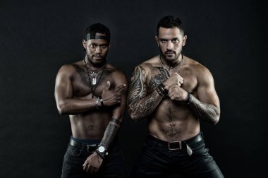 Atletler çıplak kas sandıkları ve pazı ile kendine güvenen yüzleri. Maço kas dövmeli torsolar ile çekici, koyu arka plan bak. Dövme sanat kavramı. Çocuklar sporcular seksi kas torsolar ile