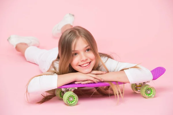 Concepto de pasatiempo para adolescentes. A la chica le gusta montar en monopatín y estilo de vida deportivo. Chica en la cara sonriente posando con tablero de penique, fondo rosa. Niña con el pelo largo listo para montar penny board —  Fotos de Stock