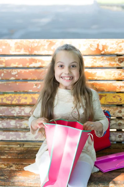 Flicka på glada ansikte uppackning kassar eller presenter, bänk på bakgrund. Flicka överraskad av unexpectable julklappar eller presenter. Kid flicka med långt hår entusiastiska presenterar. Överraskning-konceptet — Stockfoto