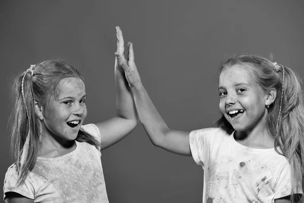 Los niños con colas de caballo hacen chocar los cinco. Amiga. Las colegialas tienen manchas de pintura — Foto de Stock