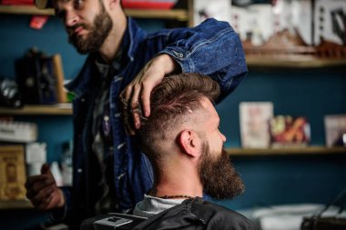 Hipster istemci taze saç kesimi veya saç modeli ile. Styling saç balmumu ile sakallı istemcisinin eller tarafından berber. Sakal ve bıyık salonların sandalye, raflar arka plan üzerinde olan adam. Berber kavramı