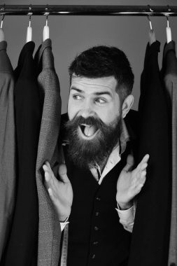 Moda giysiler. Mavi arka plan üzerinde özel ceketler yakınındaki meraklı gülümsemeyle terzi.