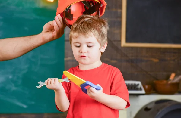 Koncentrált gyerek lenézett az eszközök a kezében. Fiú tanulási új készségek. Levette a sisakot fia apa — Stock Fotó