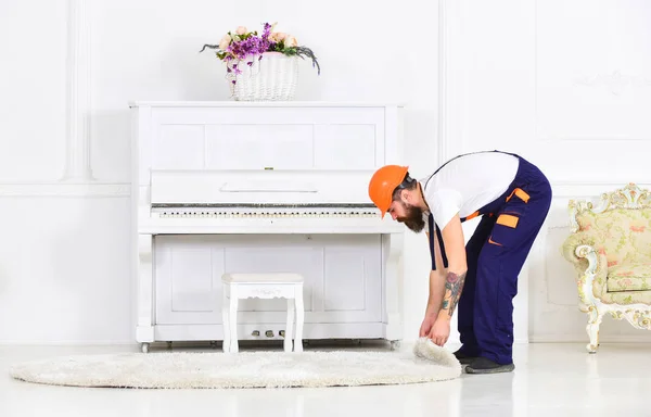 Trabajador doblado enrollando una alfombra. Hombre con tatuaje en el brazo quitando alfombra blanca de la habitación. Concepto de renovación del hogar — Foto de Stock