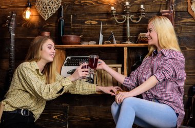 Rahatlatıcı ve mulled şarap içme kızlar. Gülümseyen yüzler kareli giysiler kutlayan arkadaşlar. Dostluk kavramı. Arkadaşlar rahat kıyafetler süre kutlama şarap, ahşap iç ile eğleniyor