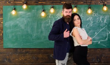 Öğretmen ve sıkı öğretmen rahat görünüyor. Bayan ve birlikte okulda çalışan hippi. Ortaklar kavramı. Sakal ve seksi kız öğretmen stand sınıfta, kara tahta arka plan ile adam