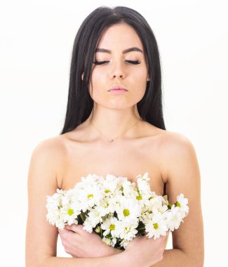 Cilt bakım kavramı. Sakin yüz kız çıplak durumda ve papatya çiçeği göğüs önünde tutar. Sağlıklı ciltle pürüzsüz kadınla çekici görünüyor. Göğüsler üzerinde beyaz izole çiçekli Lady kapsar