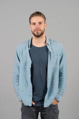 Katı sakallı adam günlük kıyafetler giyer, gri arka plan. Tıraşsız sakallı adam yakışıklı ve bakımlı görünüyor. Sakallı, çekici ve saç stili olan adam. Erkeklik kavramı