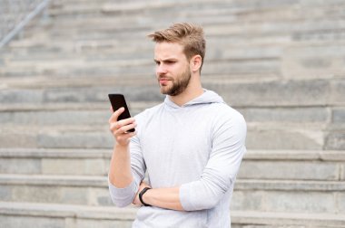 Sakallı adam akıllı telefon, merdiven ile kentsel arka plan ile yürür. Blogger'ı kullanmak smartphone akarsu video online. Adam blogger video konferans smartphone kullanarak. Blogger kavramı