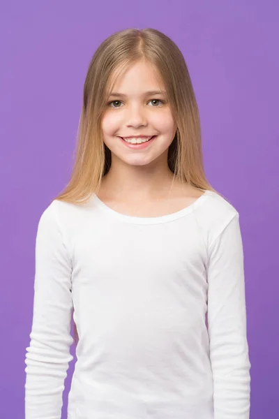 Girl on smiling face with long hair wears white shirt, violet background. Kid girl with long hair looks adorable. Hairstyle and hair care concept. Girl likes to look cute, stylish and fashionable — Stock Photo, Image