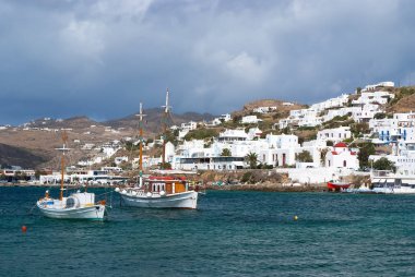 Mykonos, Yunanistan - 04 Mayıs 2010: Bulutlu gökyüzü deniz, balıkçı köyü. Yalı evleri. Dağ manzarası gemilerde mavi denizde. Adada tatil yaz. Yolculuk tutkusu ve kavram seyahat